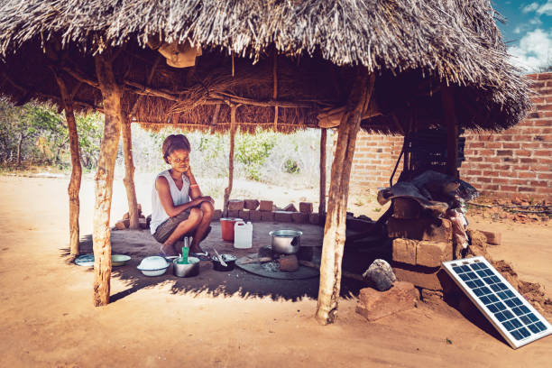 Africa, Village Life, Cooking, Routine - An African Girl Cooking Corn Maze, their Staple Food on a wood fire stove under a hut